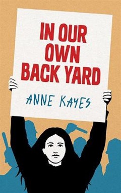 A girl holding a sign in protest with the title and author's name written on it.